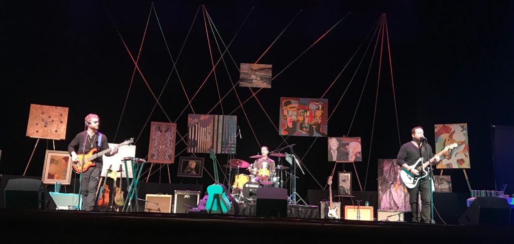 Whiskey Zulu band performing on stage with artwork in background